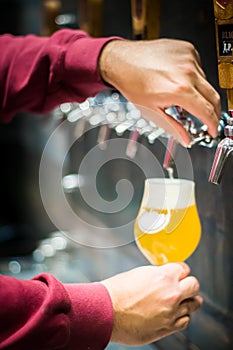 Close up photo of some beer taps and a man serving