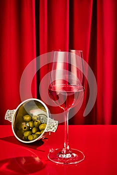 Close up photo of sweet red, pink seasoned wine served in high glass classy with olives in plate on bar counter at