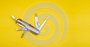 Close up photo of swiss army knife on yellow background with copy space