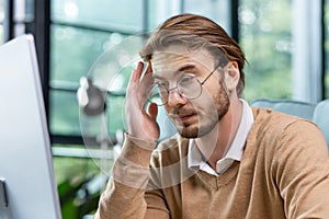 Close-up photo. Tired exhausted man, office worker, manager or freelancer sitting at his desk, tired of working on