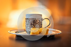 Close-up photo of a traditional Turkish dibek coffee served with porcelain chinaware cup and Turkish delight on a table