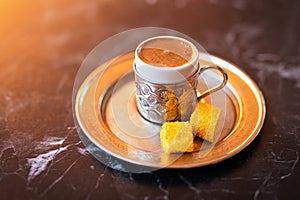 Close-up photo of a traditional Turkish dibek coffee served with porcelain chinaware cup and Turkish delight on a table