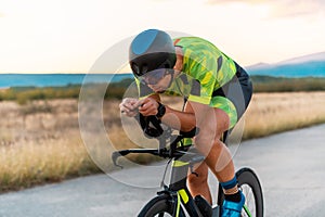 Close up photo of triathlete riding his bicycle during sunset, preparing for a marathon. The warm colors of the sky