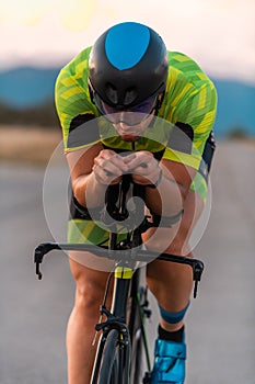 Close up photo of triathlete riding his bicycle during sunset, preparing for a marathon. The warm colors of the sky