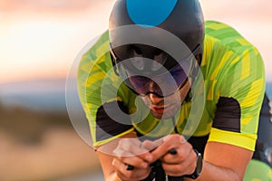 Close up photo of triathlete riding his bicycle during sunset, preparing for a marathon. The warm colors of the sky