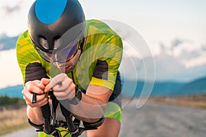 Close up photo of triathlete riding his bicycle during sunset, preparing for a marathon. The warm colors of the sky