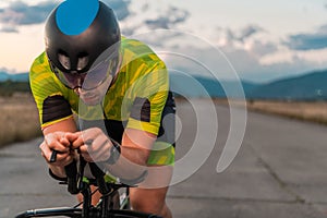 Close up photo of triathlete riding his bicycle during sunset, preparing for a marathon. The warm colors of the sky