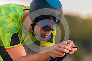 Close up photo of triathlete riding his bicycle during sunset, preparing for a marathon. The warm colors of the sky