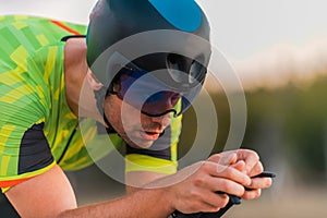 Close up photo of triathlete riding his bicycle during sunset, preparing for a marathon. The warm colors of the sky