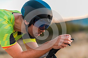 Close up photo of triathlete riding his bicycle during sunset, preparing for a marathon. The warm colors of the sky