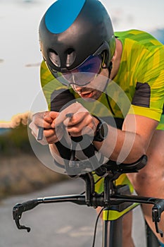 Close up photo of triathlete riding his bicycle during sunset, preparing for a marathon. The warm colors of the sky