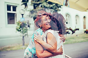 Close-up photo of two emotional happy senior female friends hugging each other