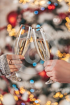 Close up, photo of two people holding glasses of champagne on xmas bokeh background