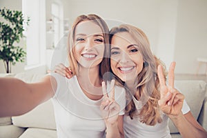 Close up photo of two people mum and teen daughter holding hands arms telephone showing v-sign funky make take selfie