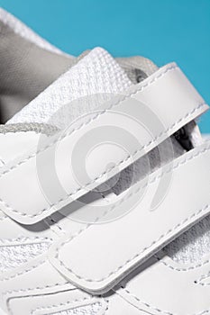 A close-up photo of the Velcro fastener of white sneakers. Children's sports sneakers made of leather with ventilation