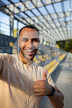 Close-up photo. Vertical photo. Young African American male sportsman stands in headphones at the stadium, takes a