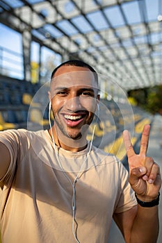 Close-up photo. Vertical photo. Young African American male sportsman stands in headphones at the stadium, takes a