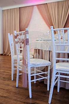 photo of white chairs decorated with brown textil in a banquet hall in white and brown colors decorated for the event photo