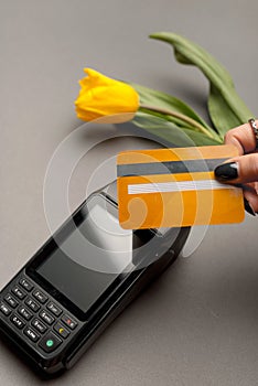 Close up photo of woman paying with credit card by paypass near yellow tulip
