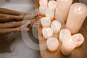 Close up photo of woman& x27;s body in spa bathtub with wooden table vase of plant candle. Modern spa center