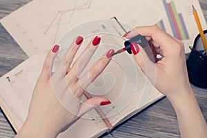 Close up photo of woman`s hands painting fingernails at workplac