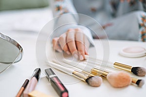 Close up photo of women\'s hand with makeup brushes, selective focus