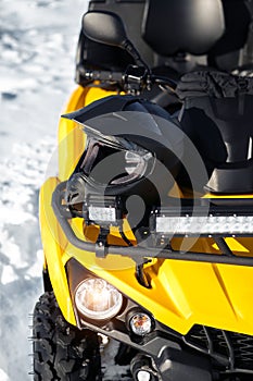Close-up photo of yellow ATV 4wd quad bike stand in heavy snow with deep wheel track.