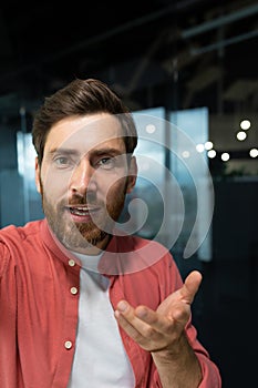 Close-up photo. Young businessman, freelancer, programmer conducts a video conference on a video call, holds a phone in