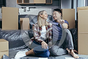 Close-up photo of a young family in a new apartment holding the keys to the house, a multiracial couple sitting in the living room