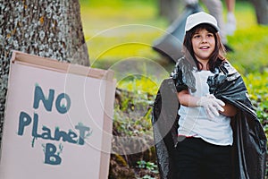 Close up photo of a young girl in a white cap and protective gloves covered her shoulders with a garbage bag and a