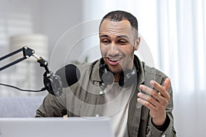 Close-up photo. Young hispanic man sitting at home wearing headphones, talking into a microphone on a video call from a