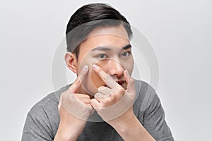 Close up photo of young man looking for acnes on his face