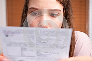 Close up photo of a young woman doing domestic accounting paperwork bills and invoices worried and stressed at home.