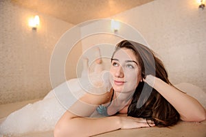 photo of a young woman in white foam relaxing in a hamam