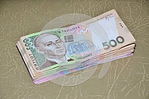 A close-up photograph of a set of Ukrainian money with a face value of 500 hryvnia, lying on a brown leather surface. Background