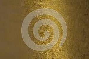 A close-up photograph of a synthetic golden fabric.