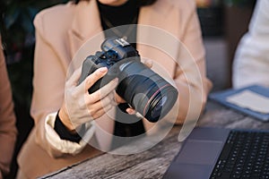 Close-up of photographer holding mirrorless camera and checking pictures.