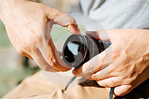 Close-up of a photographer's male hands putting a professional protective filter on the camera lens, outdoors