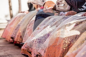 Fallera dresses, bright colors and reflections in these typical costumes of the fallas of Valencia. Falleras seated in a public photo