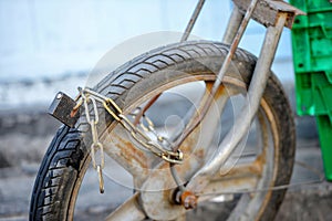Close-up photography. An old motorcycle front wheel is locked in the iron chain.