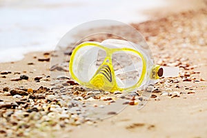 Close up photography of yellow snorkling mask standing in the sand.Underwater diving concept