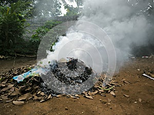Close up photos burn dry fallen leaves that produce thick smoke.