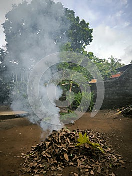 Close up photos burn dry fallen leaves that produce thick smoke.