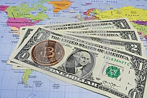 Close up physical bitcoin coin with US dollars and world map.