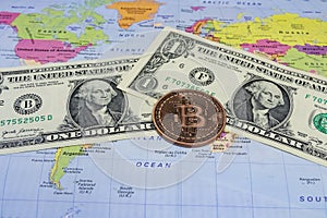 Close up physical bitcoin coin with US dollars and world map.