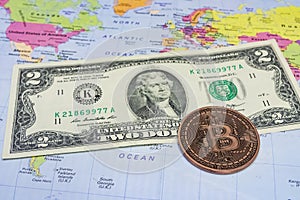 Close up physical bitcoin coin with US dollars and world map.