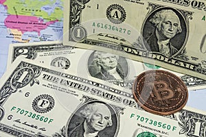 Close up physical bitcoin coin with US dollars and world map.