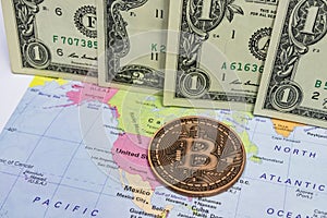 Close up physical bitcoin coin with US dollars and world map.