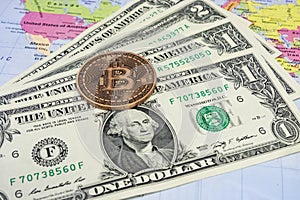 Close up physical bitcoin coin with US dollars and world map.