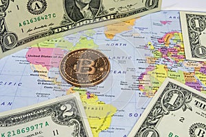 Close up physical bitcoin coin with US dollars and world map.